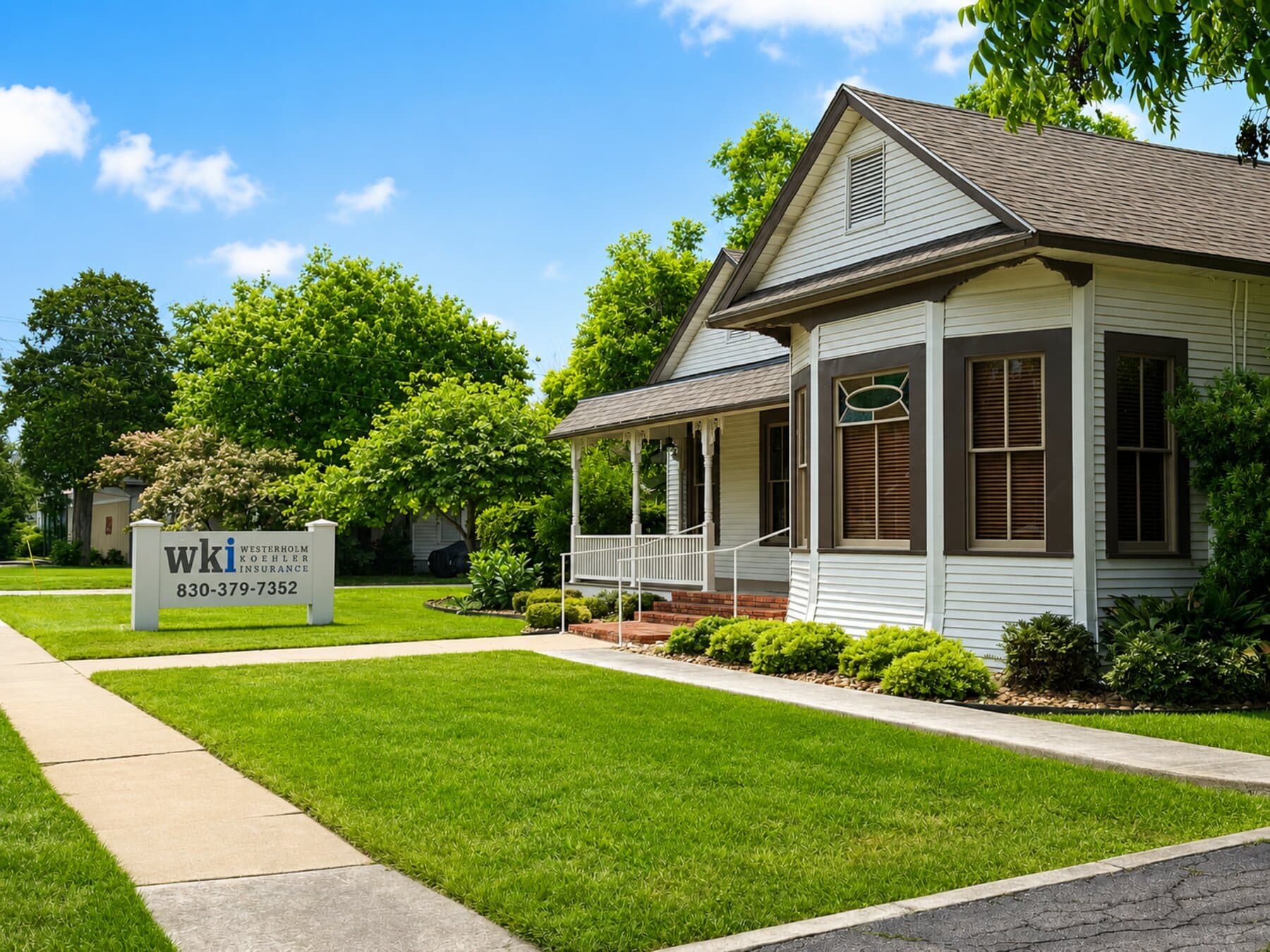 The WKI Texas office at 533 E. Court Street — sign on the lawn, historic home that houses the agency, mid-morning Seguin light